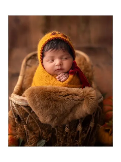 A close-up of the newborn in the pumpkin hat, showing the rich colors and textures of the autumn theme.