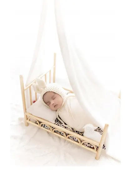 Sweet dreams in a tiny bed. A swaddled newborn with a bunny hat sleeps on a miniature wooden bed, creating an incredibly cute and gentle portrait that highlights how small and precious they are.