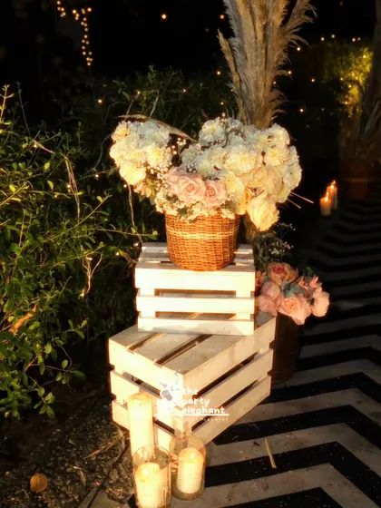 Rustic and chic details, like these white wooden crates, floral arrangements, and pillar candles, added layers of texture and warmth to the outdoor party decor.