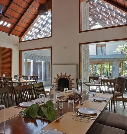 The dining area of this nature resort features high, tiled roofs and large, open windows. This design maximizes natural light and ventilation, allowing diners to feel connected to the beautiful estate grounds outside.