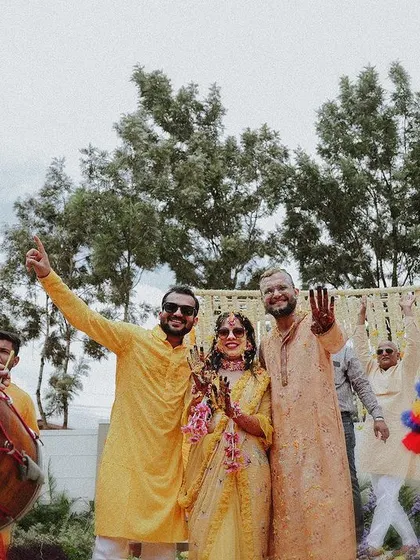The couple with dhol players, celebrating with energy and traditional music at their Haldi ceremony.