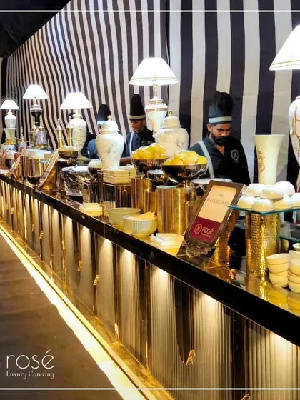 A stylish buffet counter with a black-and-white striped backdrop. The gold accents and modern lamps create a chic and contemporary look for your event.