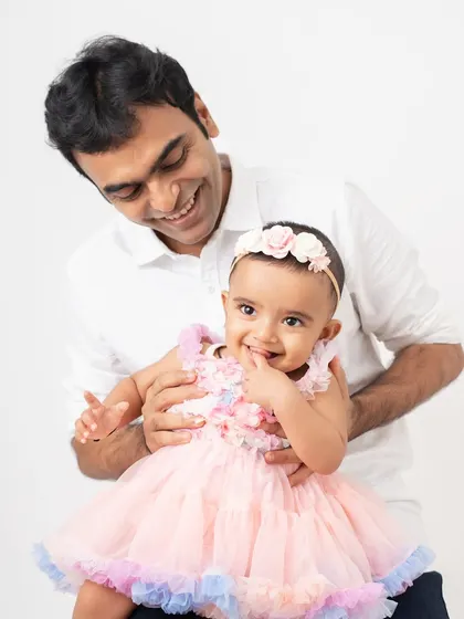 A playful moment between a father and his daughter. Her little hand in her mouth and his happy smile make this a perfectly candid and adorable shot.