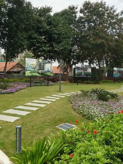 A park-like garden space within a residential community, featuring winding stone pathways, colorful flower beds, and mature trees. This is an example of creating beautiful common areas for residents.