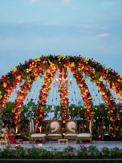 The floral dome mandap at dusk, with the city skyline in the background. This view captures the grandeur of the structure and its beautiful integration with the open-air rooftop venue.