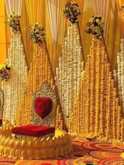A grand and royal Haldi seating with a backdrop of marigold and tuberose strings. The ornate golden chairs add a touch of luxury to the traditional setup.