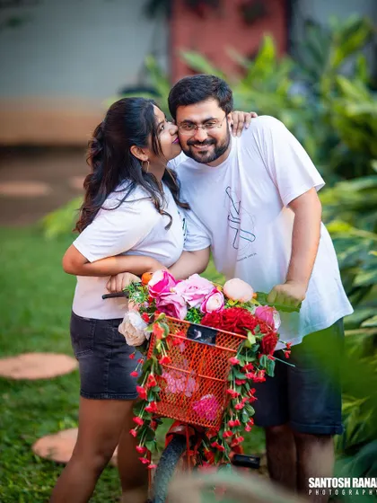 A cute kiss on the cheek, captured during a fun pre-wedding shoot with a bicycle prop.
