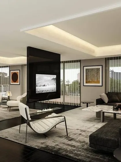 This private residence in Gurugram uses a minimalist layout to create an expansive, open living and dining zone. A central black partition houses the TV, cleverly dividing the large space into more intimate seating areas without closing it off.