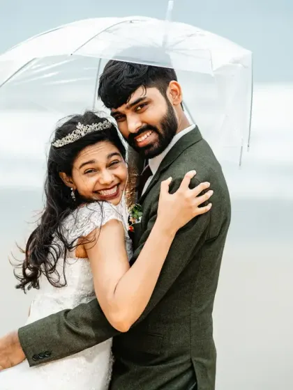 A candid moment of happiness during a rainy Goa photoshoot. The genuine smiles and warm embrace under the umbrella show that even a little rain can't dampen the joy of the day.