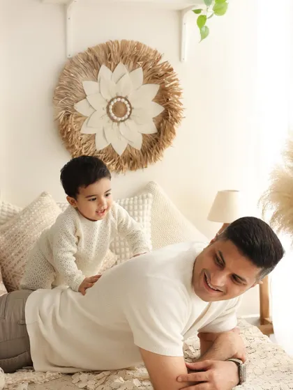 A moment of play and connection. This dad lets his son climb on his back, a simple game that creates a beautiful, candid photograph of their bond in our boho studio.