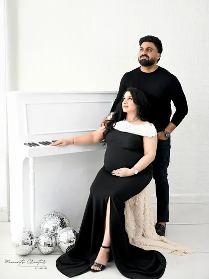 A sophisticated couple's portrait by the white piano. The classic black outfits and clean white background create a modern and elegant look.