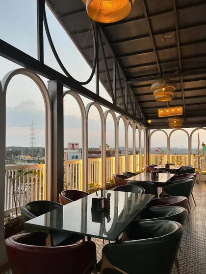 The dining area at 'The Soda Factory' features large arched windows that frame the outside view. We added planters along the windows to bring the greenery inside, connecting the interior space with the natural landscape.