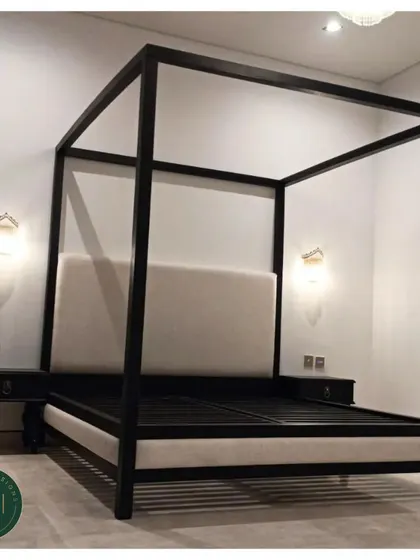 A striking four-poster bed in a black finish with a contrasting cream-colored upholstered headboard and base. This piece combines classic form with a modern, high-contrast color palette for a dramatic effect.
