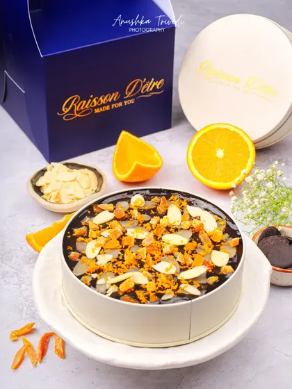 A rich chocolate orange cake in a tin, topped with almonds and orange zest, ready for gifting.