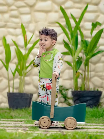 Look at that cool attitude! This little boy is full of swag as he stands with his wooden cart in our green and lush garden space.
