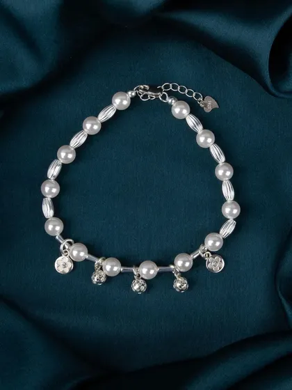 A pearl bracelet with dangling silver bell-shaped charms.