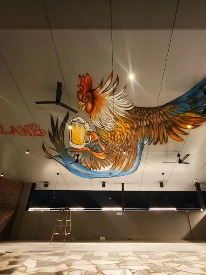 Another angle of the ceiling mural, highlighting the vibrant colors and details of the rooster clutching a beer.