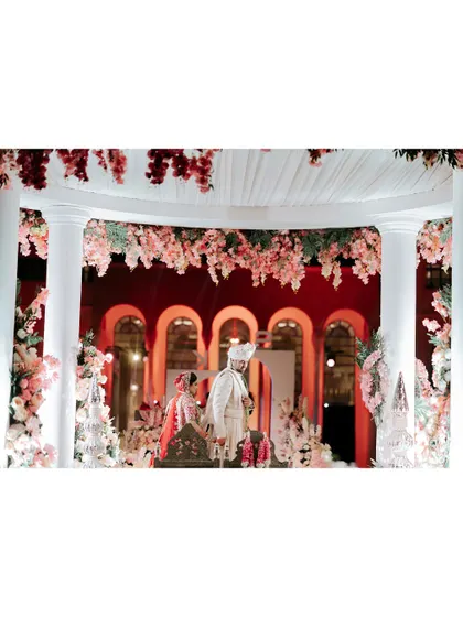 The wedding mandap in Doha, beautifully decorated with white drapes and pink flowers, creating a soft and romantic atmosphere.