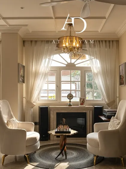 This cozy seating nook features vintage-style armchairs by a fireplace, creating a perfect spot for conversation or reading, bathed in natural light.