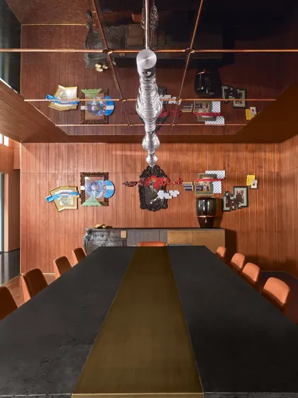 Another view of the dining room, highlighting the reflective ceiling, artwork by Nandan Ghiya, and a Brokis light from Lightbox. Every meal here becomes a luxurious affair surrounded by art.