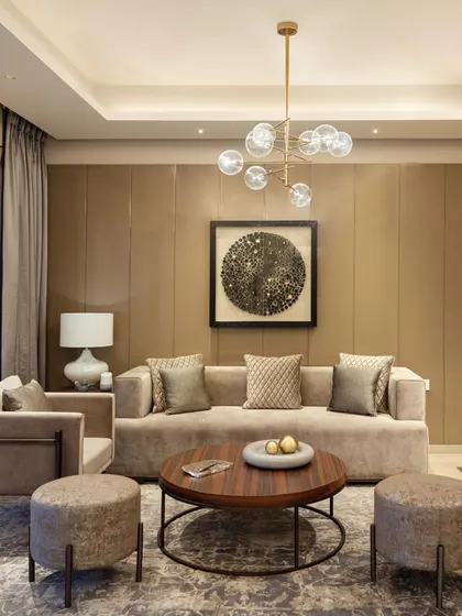 A contemporary living room with a neutral color palette, clean lines, and a modern chandelier, representing a sophisticated and understated design approach.