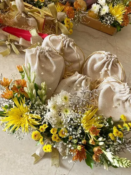 A close-up of one of my floral platters for a wedding. This one holds small, elegantly wrapped potlis, surrounded by a vibrant bouquet of fresh flowers.