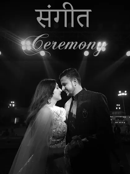 A classic black and white Sangeet portrait. The dramatic stage lighting and the couple's intimate pose create a timeless and romantic image that feels like a movie still.