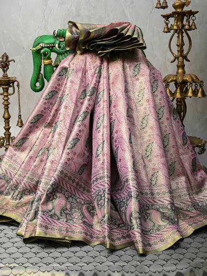 This dusty pink Banarasi silk saree is woven with intricate paisley and floral patterns in a darker thread, creating a subtle and sophisticated brocade effect.