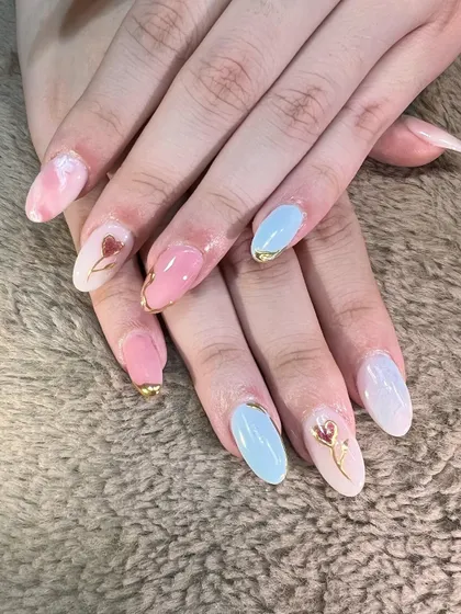 A romantic and artistic set. Soft pink and baby blue nails are accented with delicate gold chrome details and tiny, hand-painted tulip illustrations.
