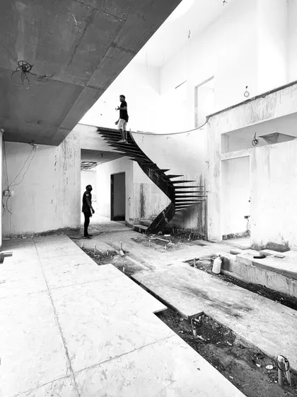 A duplicate view of the staircase in the raw construction space, with workers providing a sense of scale.