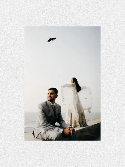 An artistic composition with the couple by the sea and a bird flying overhead. It feels like a moment of freedom and new beginnings.