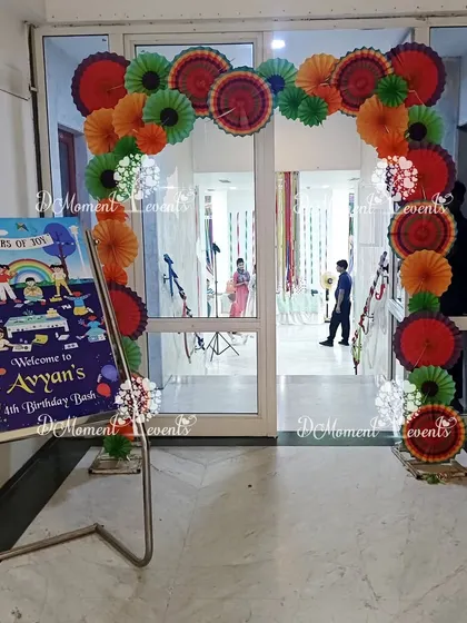 The entrance to the "Colors of Joy" art party, featuring a welcome sign and an arch made of colorful paper fans instead of balloons.