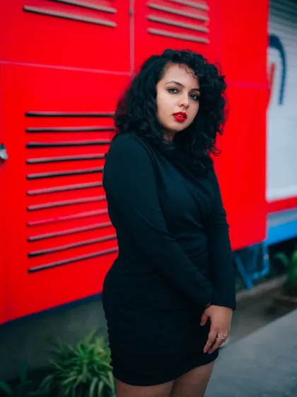 A portrait of a model in a black dress against a vibrant red background. The strong color contrast and her confident pose make this a very striking image.