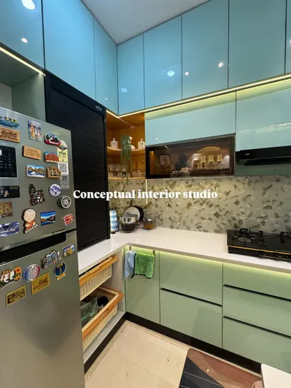 An inspiration shot of a dream kitchen. This design features a beautiful terrazzo-style backsplash, dual-tone pastel green and blue cabinets, and a roller shutter for the appliance garage.