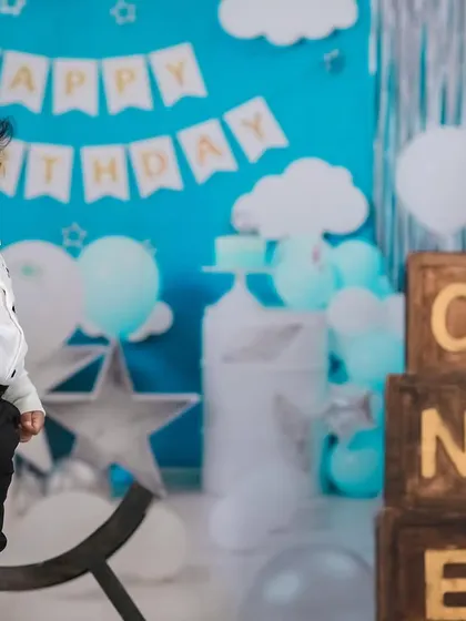 A handsome little man celebrating his first birthday. The 'Happy Birthday' banner and 'ONE' blocks create a perfect backdrop for this milestone photo.