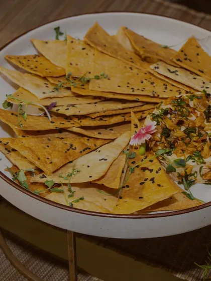 A bowl of crispy, seasoned tortilla chips served with a gourmet dip. This classic appetizer is elevated through high-quality ingredients and thoughtful presentation with microgreens.