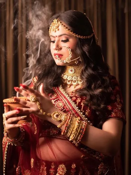 A royal bride captured in a timeless moment. The makeup is classic and regal, with defined eyes and a deep red lip, perfectly suited for her traditional look.