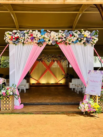 The entrance to the Mayra ceremony, featuring a lovely arch of multicolored flowers and elegant pink and white drapes.
