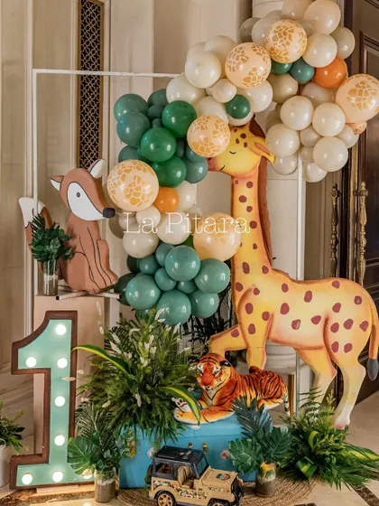 A playful arrangement of a giraffe and tiger prop with a light-up '1' and a balloon garland, perfect for a first birthday photo op.