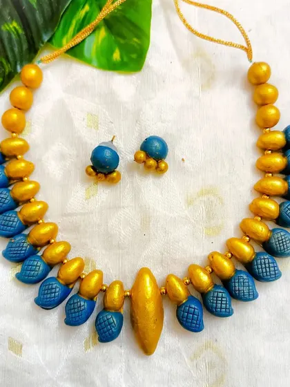A sleek terracotta choker made of blue and gold beads. These are simple, elegant, and perfect for layering or wearing on their own.