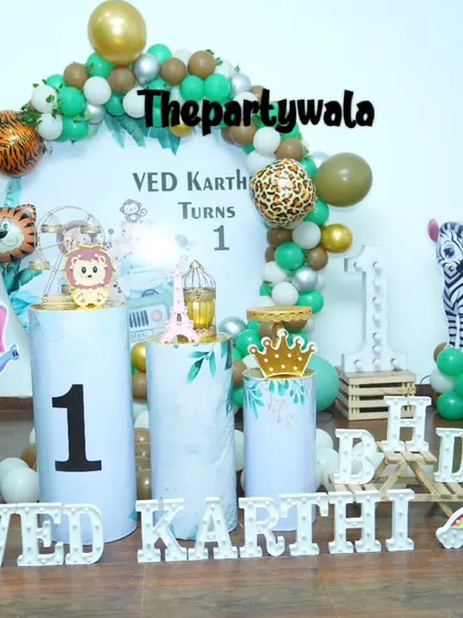 A jungle theme with lots of fun details, including animal print foil balloons and a light-up "ONE" sign. The themed pedestals add to the safari vibe.