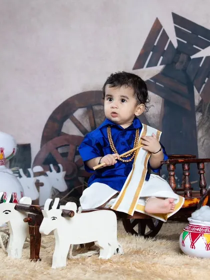 This little boy looks thoughtful as he poses in a village scene with miniature bulls.