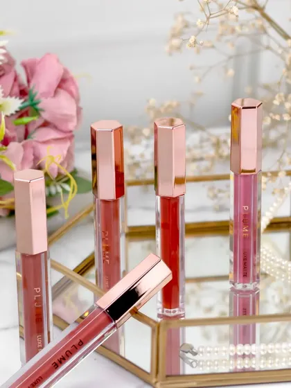 This arrangement on a mirrored tray uses reflections to create a sense of depth and luxury. The soft pink flowers and pearls in the background complement the rose-gold packaging of the lipsticks.