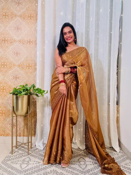 This golden tissue saree with embroidery is a stunning choice for a wedding or a grand celebration. It looks incredibly rich and festive.