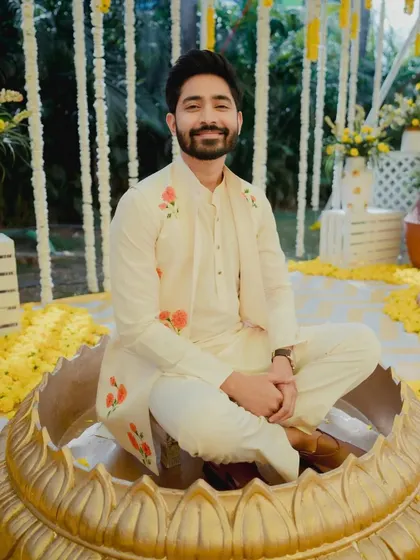 The groom, all smiles, seated in a giant golden lotus for the Haldi rituals, a unique and fun decor element.