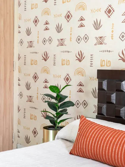The whimsical bohemian wallpaper in this guest room adds a playful and charming character, reflecting the personality of its occupant.