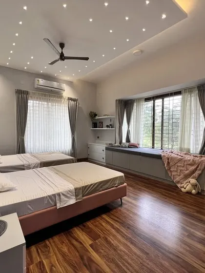 A wide view of the shared kids' room, highlighting the spacious layout. The design includes a large window seat with built-in storage, creating a perfect nook for reading and play, all under a ceiling of starry lights.