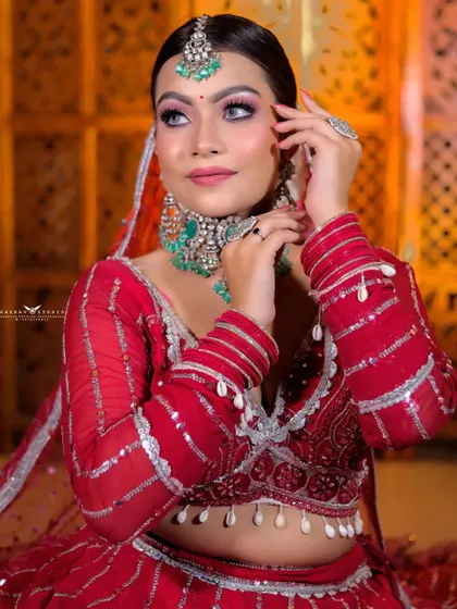 A beautiful portrait capturing the bride's side profile and her elegant hand gesture. The warm lighting enhances the richness of her red outfit.