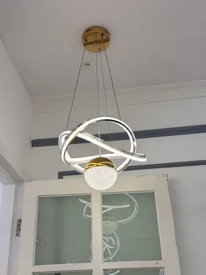 A modern pendant featuring interlocking rings and a central crystal-dusted sphere. A compact yet eye-catching design.