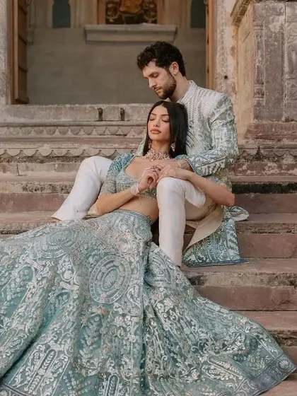 A modern fairytale look. The bride's powder blue lehenga with its sweeping train is perfectly matched by the groom's sherwani, which features the same intricate silver embroidery.